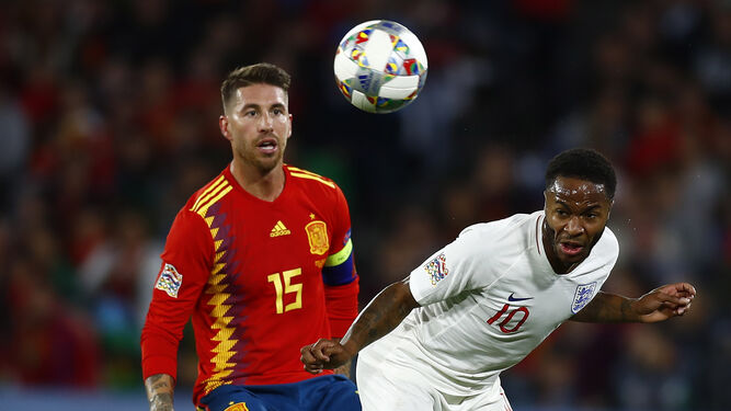 El capitán de la selección, Sergio Ramos, presiona al inglés Sterling mientras éste cabecea el balón.