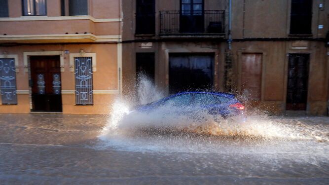 Un coche atraviesa una balsa de agua tras las fuertes lluvias.