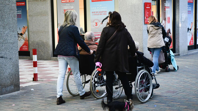 Dos mujeres ayudan a otras dos personas en sillas de ruedas.