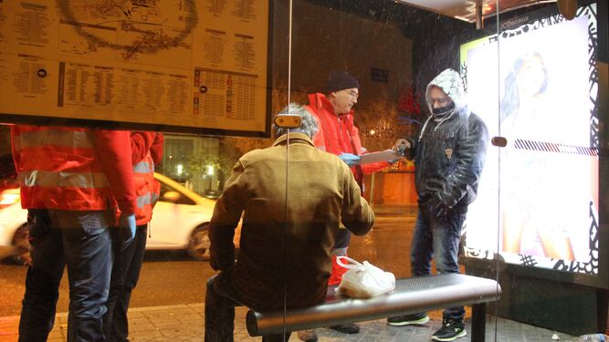 Voluntarios de Cruz Roja atienden a dos hombres que viven en la calle.