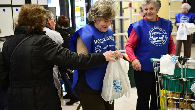 Una señora entrega una bolsa con alimentos a una de las voluntarias.