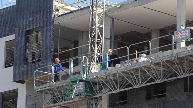 Dos trabajadores de la construcción realizan obras de edificación en un bloque de pisos.