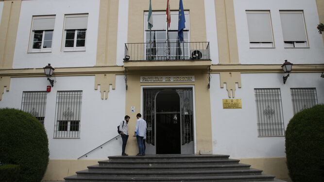 Dos alumnos conversan en la entrada principal de la Facultad de Derecho