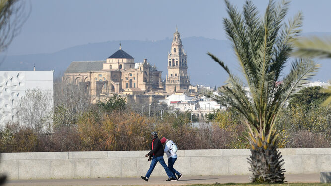 Dos personas caminan junto al río Guadalquivir con la Mezquita-Catedral al fondo