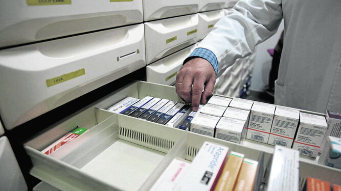 Un farmacéutico  recoge varios medicamentos de un almacén.