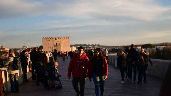 Varias personas pasean por el Puente Romano de la capital cordobesa
