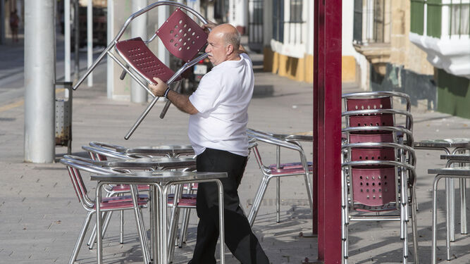 Un camarero coloca las sillas en una terraza de San Fernando.