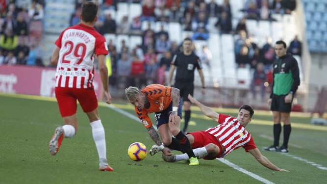 Un jugador del Osasuna trata de escapar de la presión de dos jugadores del Almería.