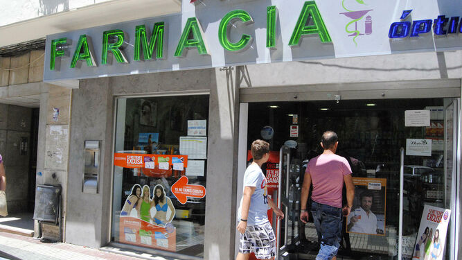 Dos usuarios acceden al interior de una oficina de farmacia de Huelva.