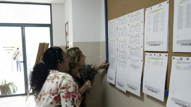 Dos mujeres observan las listas de admitidos en un centro de la capital