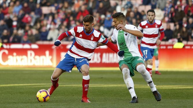 Un jugador del Extremadura intenta frenar la acción de un jugador del Granada.