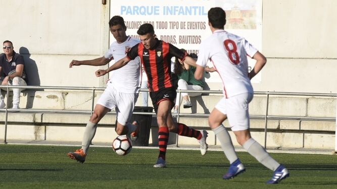 Un jugador del Séneca trata de sacar el balón jugado entre dos rivales del Sevilla.
