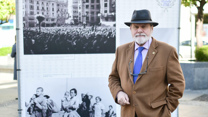 José F. Gálvez posa delante de fotografías de una exposición instalada en la plaza de las Tendillas.