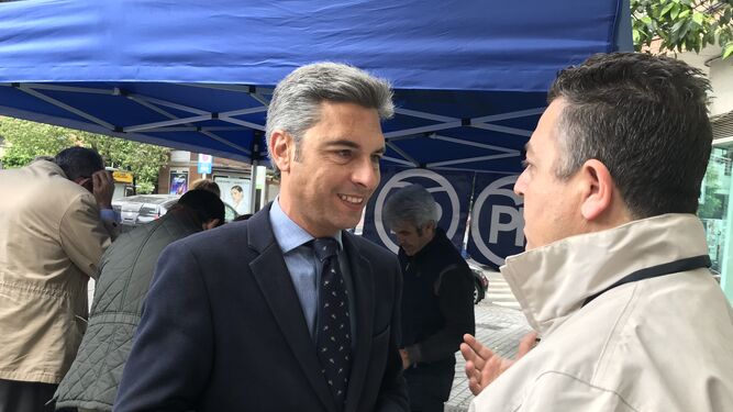 Andrés Lorite conversa con un hombre junto a la carpa de campaña del PP.