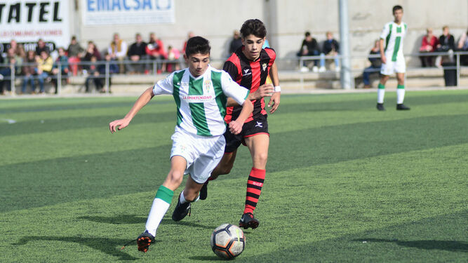 Un jugador del Córdoba se lleva el balón en presencia de uno del Séneca.