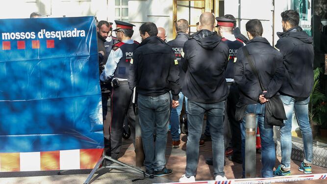 Varios agentes y sanitarios trasladan el cadáver de la joven asesinada en un bar de Barcelona.