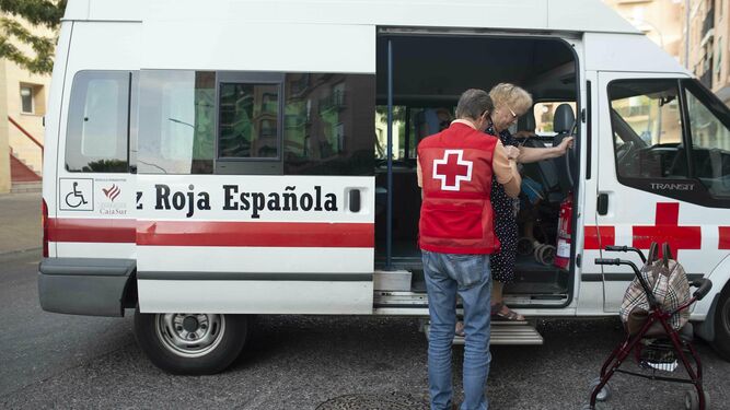 Un voluntario de Cruz Roja ayuda a una mujer a bajar de la furgoneta.