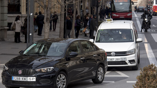 Un VTC que opera con Uber circula delante de un taxi en Granada.