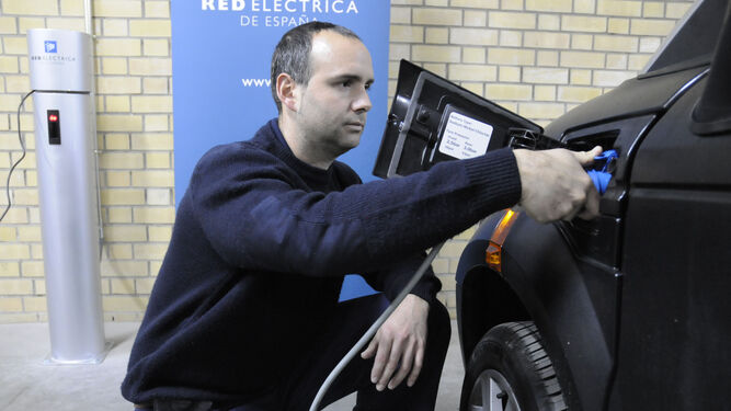Un hombre recarga un vehículo eléctrico.