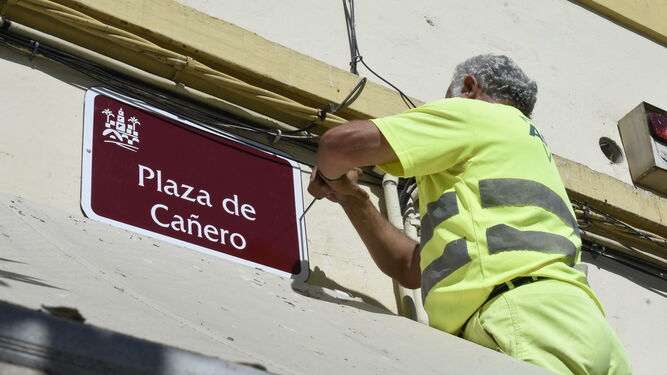 Un operario vuelve a colocar el rótulo de plaza de Cañero.