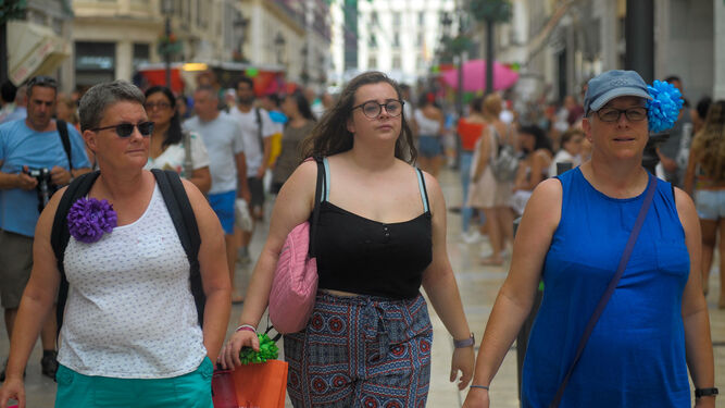 Tres mujeres extranjeras pasean por calle Larios en Feria.