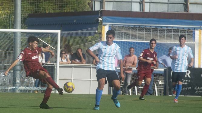 Un jugador del Córdoba se dispone a pasar el balón con la oposición de uno del Don Bosco.