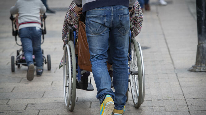 Una persona empuja la silla de ruedas de otra.
