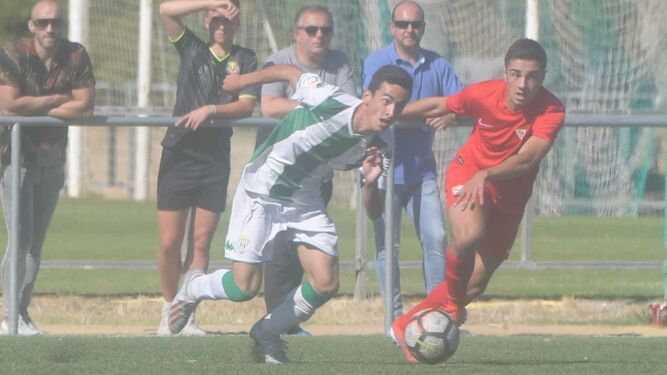Un jugador del Córdoba pugna por el balón con un rival del Sevilla.