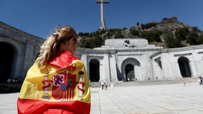 Una joven con una bandera nacional constitucional ante el Valle de los Caídos.