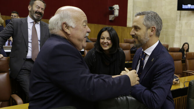 El consejero de Salud, Jesús Aguire, saluda al titular de Hacienda, Juan Bravo, en el Parlamento.