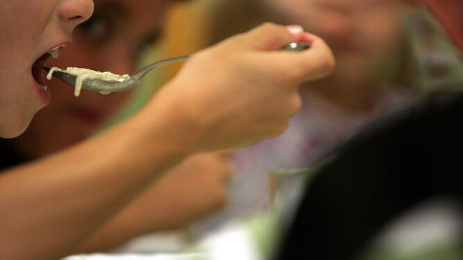 Un escolar  almuerza sopa de fideos en un comedor  escolar.