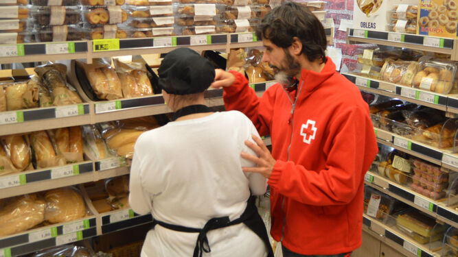 Un voluntario de Cruz Roja conversa con una alumna del curso en una tienda Proxi.