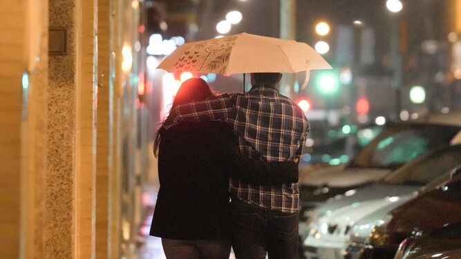 Una pareja pasea bajo la lluvia.
