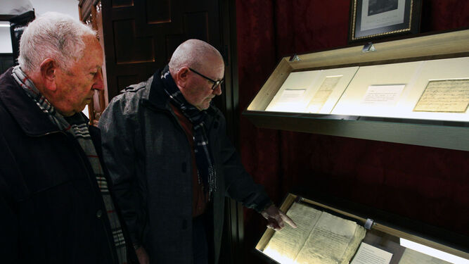 Dos personas observan algunos de los documentos del archivo de la parroquia de Santiago.