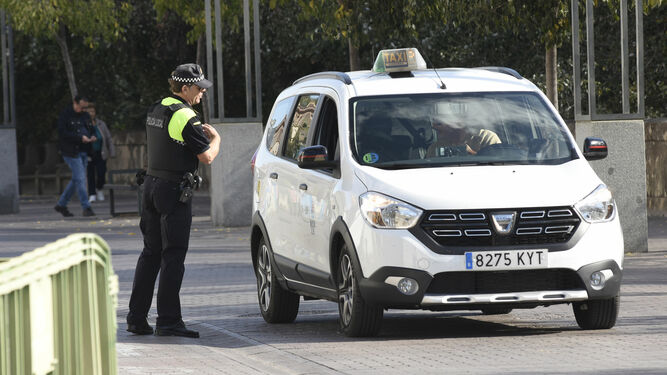 Un policía local junto a un taxi, en la Ribera.