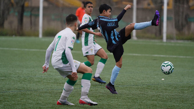 Un jugador del Don Bosco despeja el esférico en presencia de dos jugadores del Córdoba.