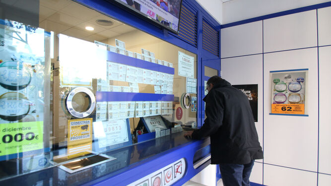 Un hombre sella un boleto en una administración de loterías.