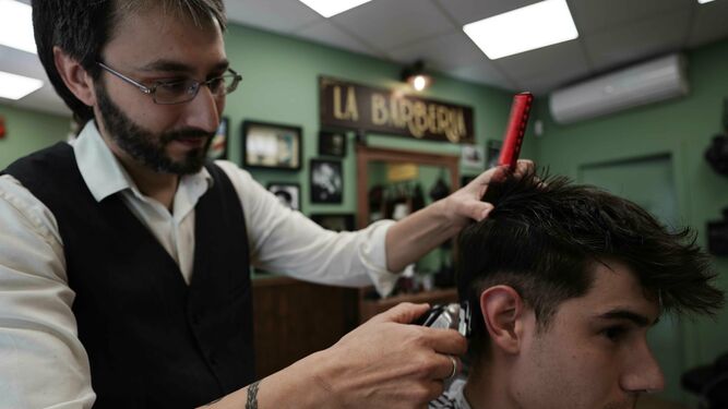 Juan Aguilar realiza un peinado en un cliente.