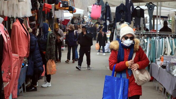 Una mujer camina con mascarilla por un mercado de Milán.