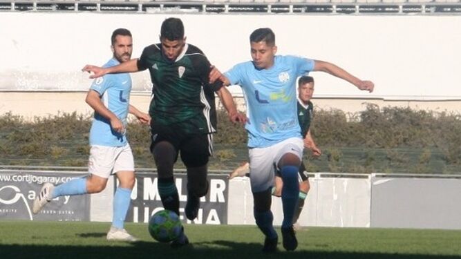 Un jugador del Ciudad de Lucena trata de cortar el avance de uno del Córdoba B.