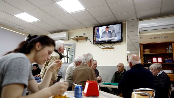Un grupo de ancianos, al fondo, juega a las cartas en un bar de Madrid.