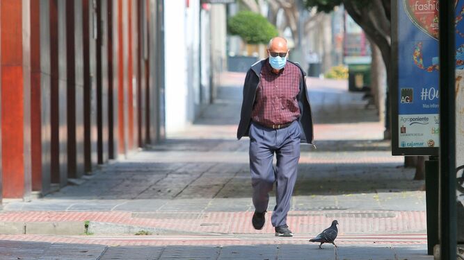 Un hombre camina por una calle vacía con una mascarilla.