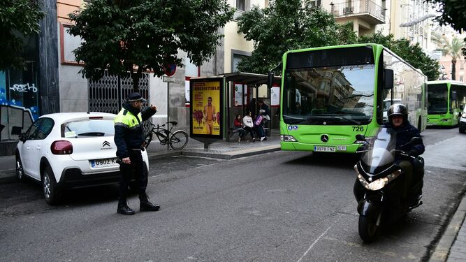 Un policía local da paso a un autobús de Aucorsa.
