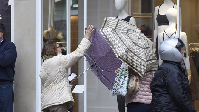 Una mujer intenta arreglar su paraguas en medio de un día de lluvia.