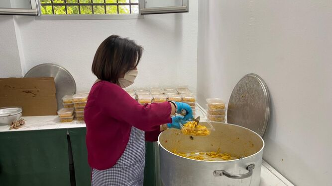 Una voluntaria de Cáritas distribuye raciones de comida.