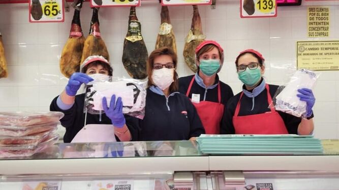 Trabajadoras de un supermercado en Nueva Carteya muestran las mascarillas confeccionadas por voluntarias del municipio.