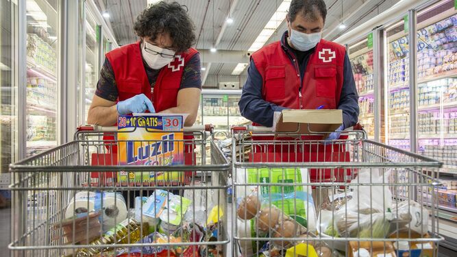 Dos voluntarios de la Cruz Roja realizan la compra en un supermercado.