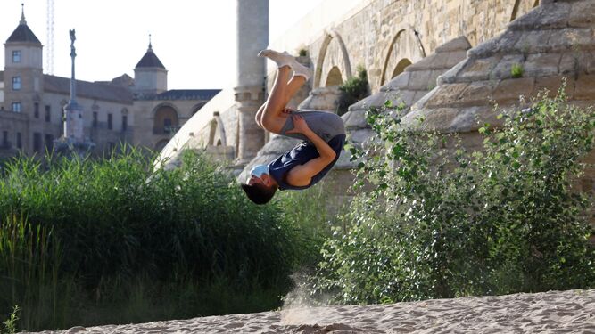 Un joven practica deporte bajo el Puente Romano de Córdoba.