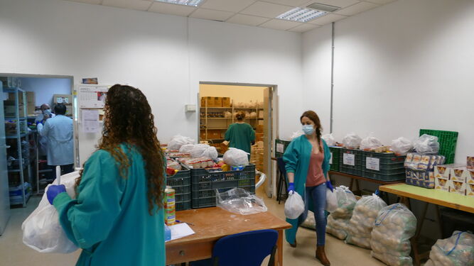 Varios trabajadores preparan las bolsas de comida antes de su reparto.