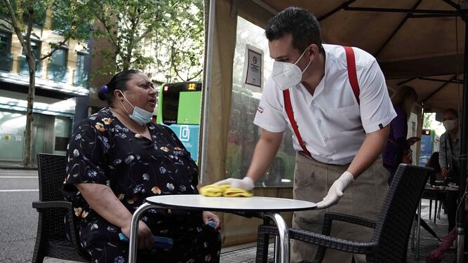 Un camarero atiende a una señora en la terraza  de un bar en el centro de Córdoba